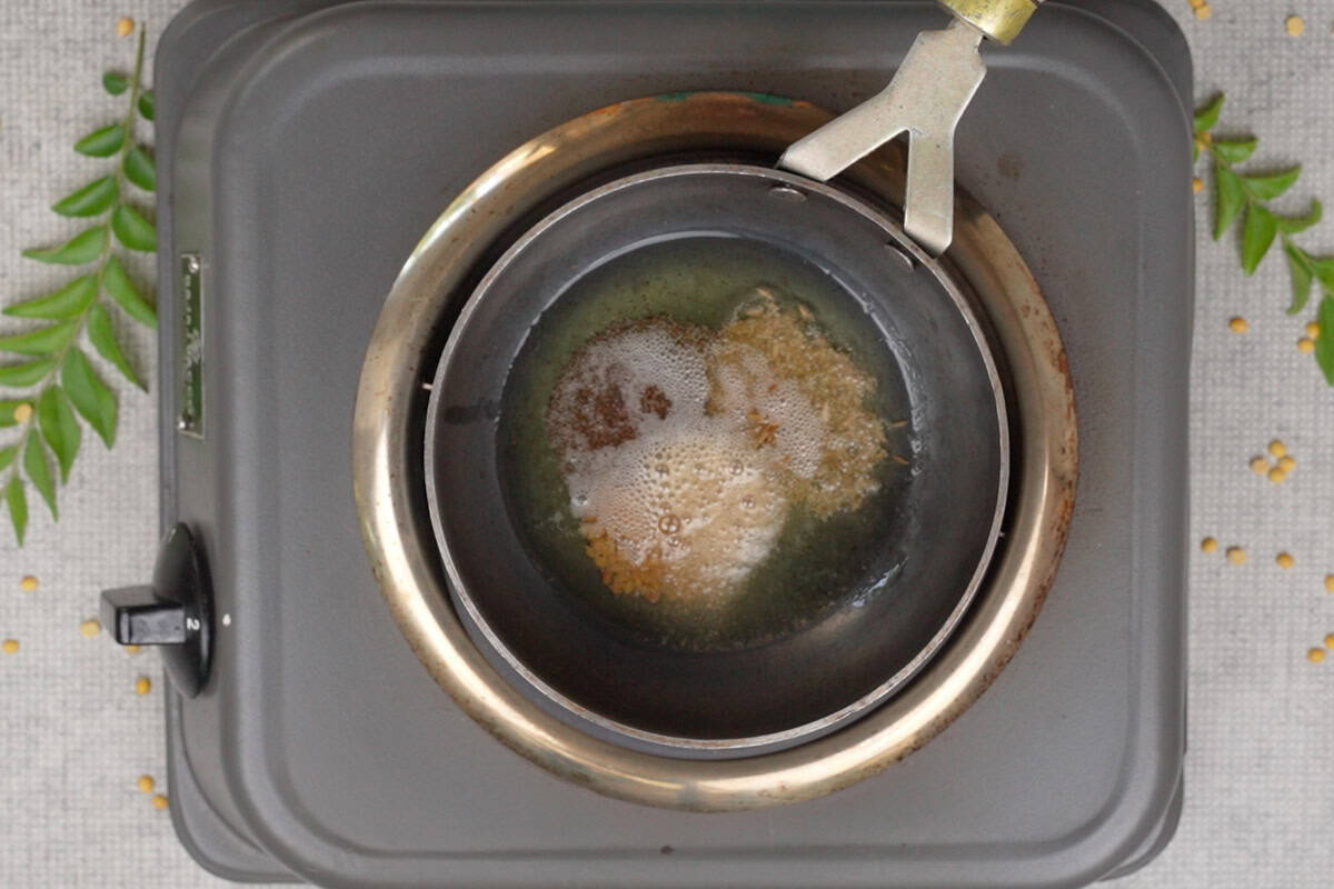 Asafetida, fenugreek seeds, mustard seeds and cumin seeds added to hot ghee in a pan.