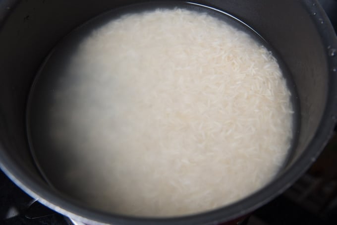 Rice for cooking in a pan along with water.