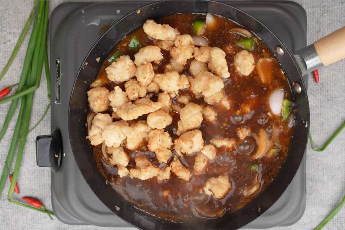 Fried chicken added to the wok.