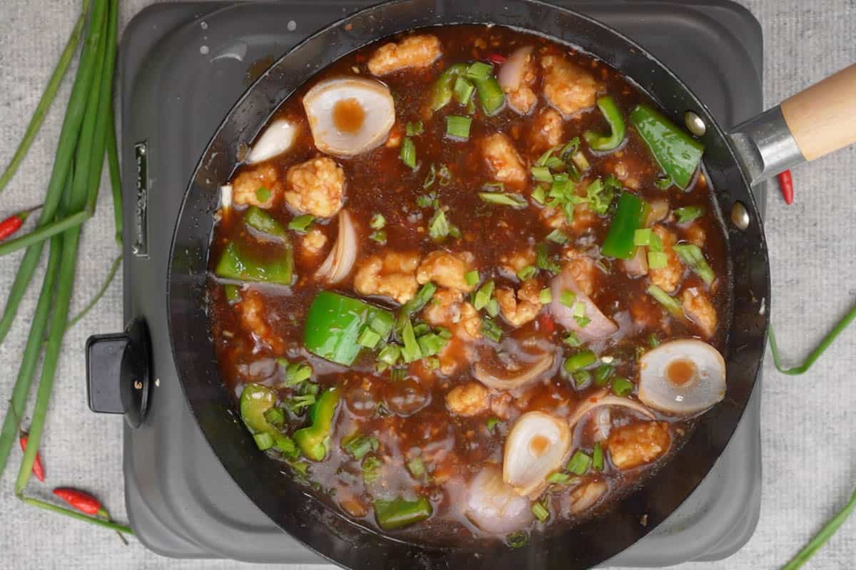 Ready chili garlic chicken garnished with spring onion greens.