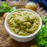 Spicy, tangy amla chutney made with Indian gooseberries and cilantro, served in a white bowl with fresh gooseberries alongside.