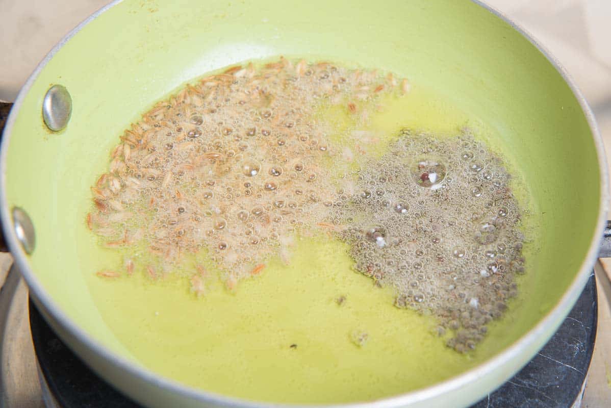 Heated ghee in a pan with cumin and mustard seeds