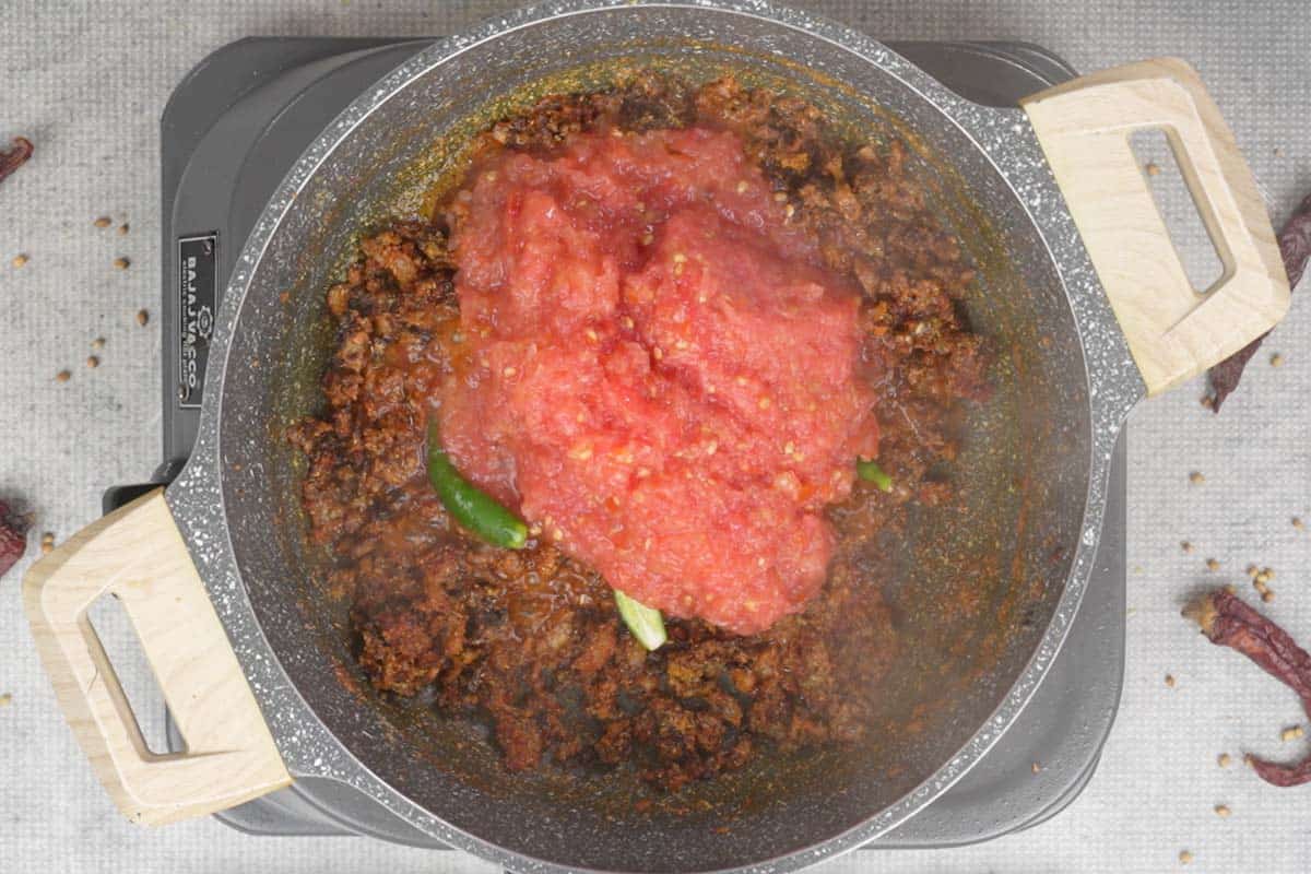 Tomatoes and green chilies added to the pan.