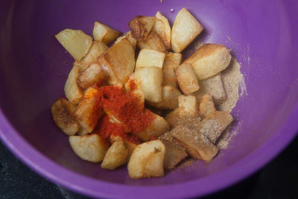 Dry spices and lemon juice added in potato cubes in a bowl