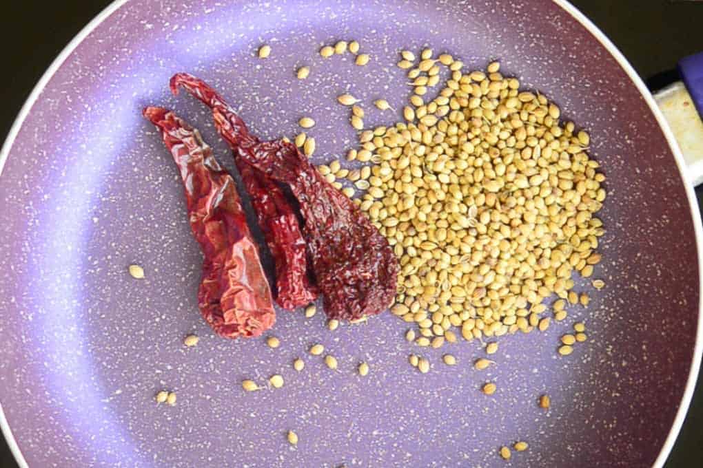 Coriander seeds and dry red chillies roasting in a pan