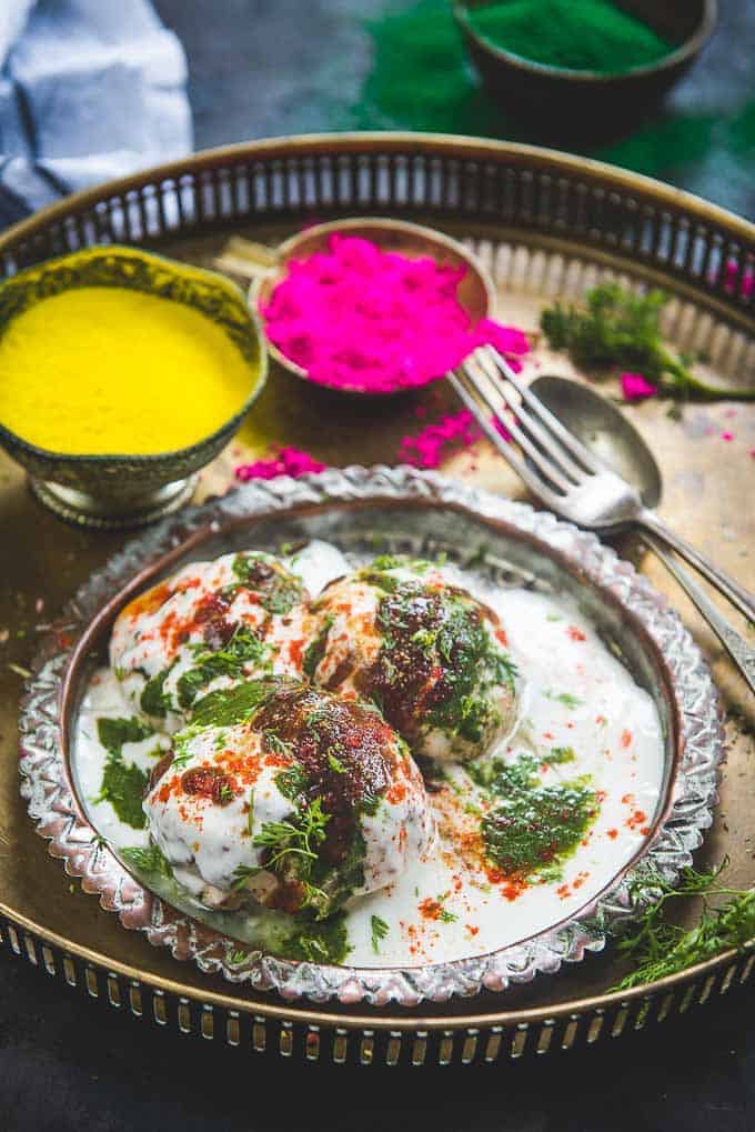 dahi vada served ina plate along with holi colours.