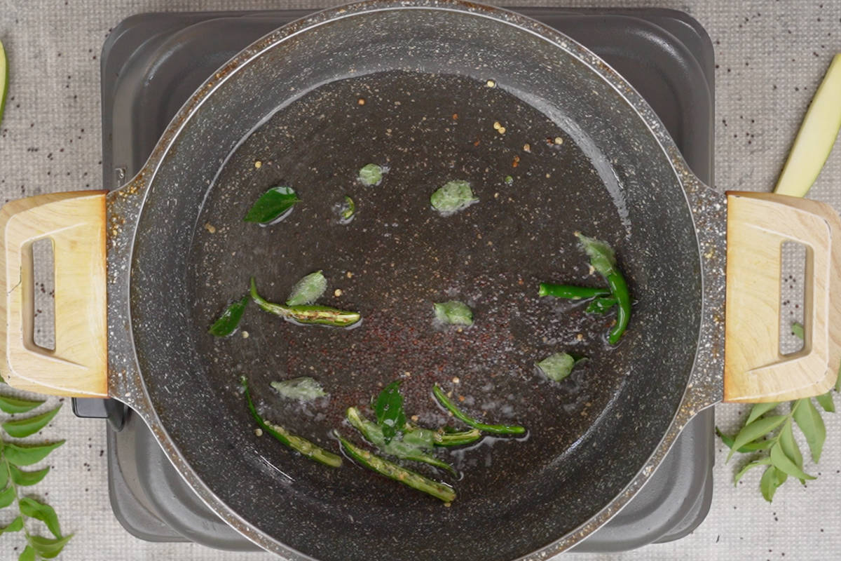 Mustard seeds, chilies and curry leaves added to hot oil in a pan.