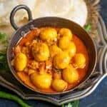 Bengali Aloo Dum (Alur Dom, Aloor Dum) is a potato curry with fried baby potatoes simmered in spicy onion, tomato, and yogurt-based gravy. Make it using my traditional recipe.