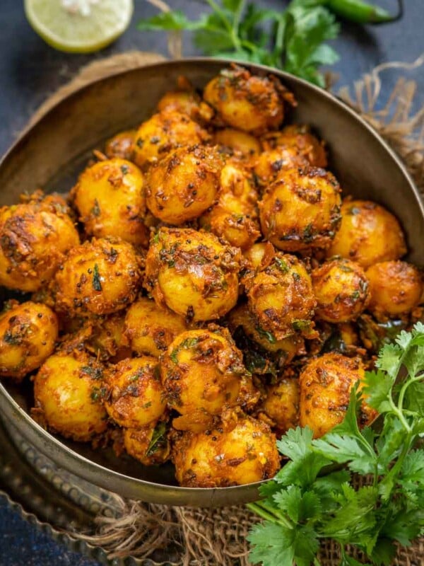This easy Bombay Potatoes (Indian Style Spicy Potatoes) recipe is made using baby potatoes, onions, tomatoes, and a few basic Indian spices. Serve it with paratha or roti for a delicious meal (vegan, can be easily made gluten-free).
