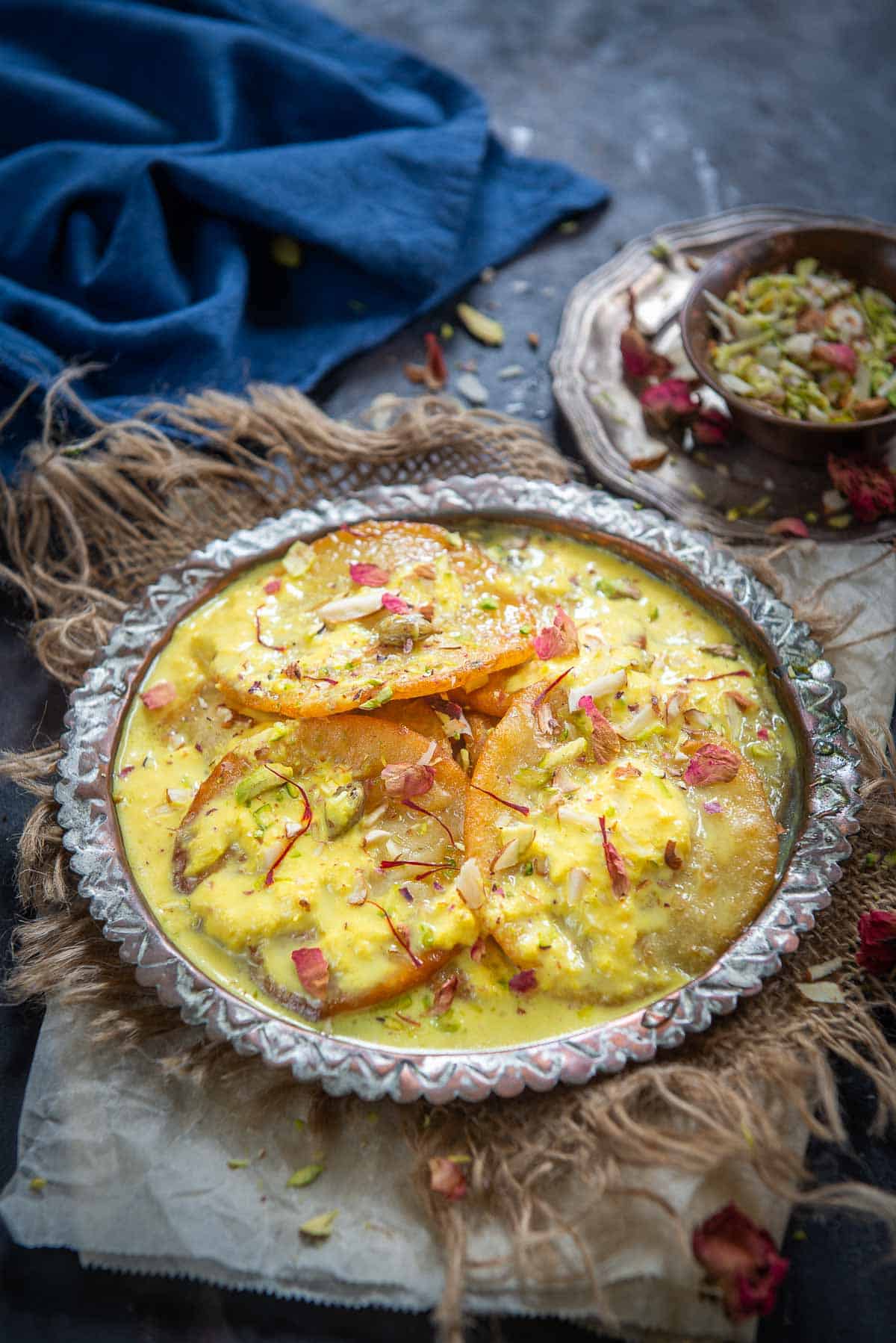 Malpua topped with rabdi served on a plate.