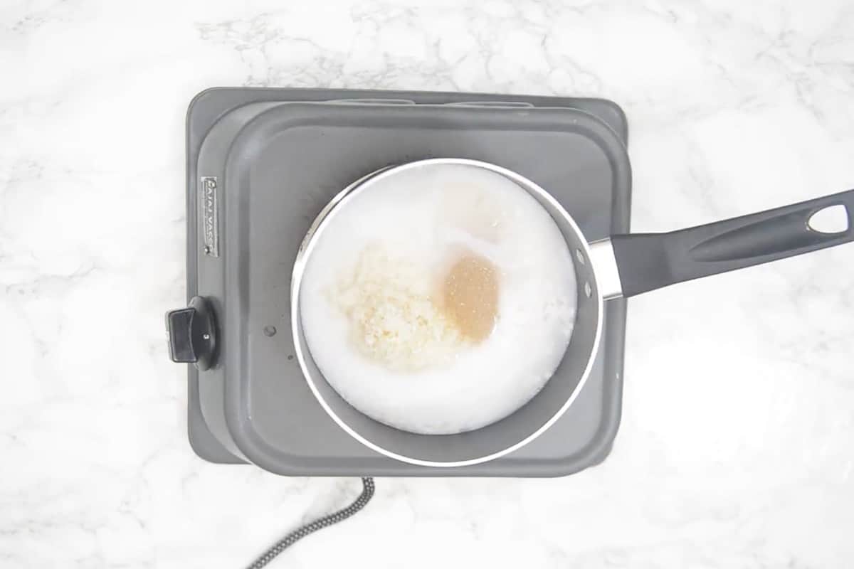 Rice added in a pan along with water, coconut milk, salt and sugar.