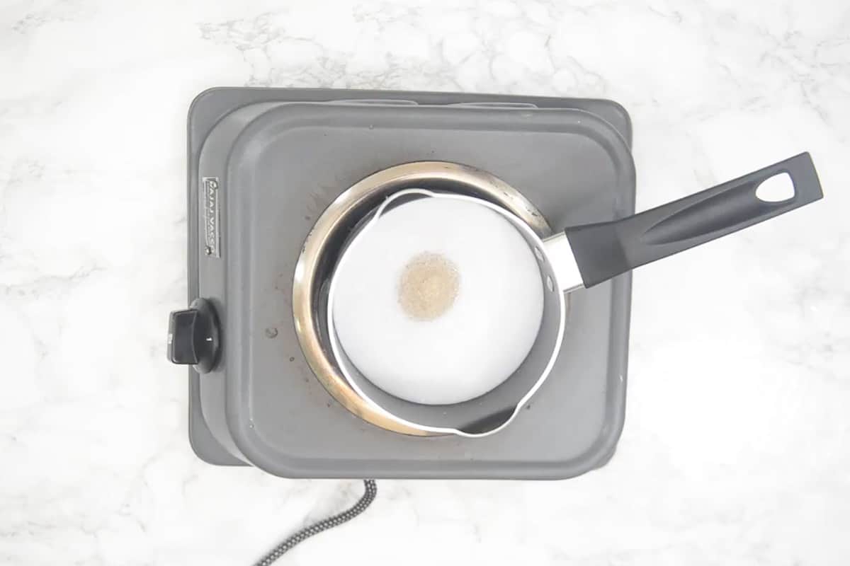 Coconut milk and sugar added in a pan.