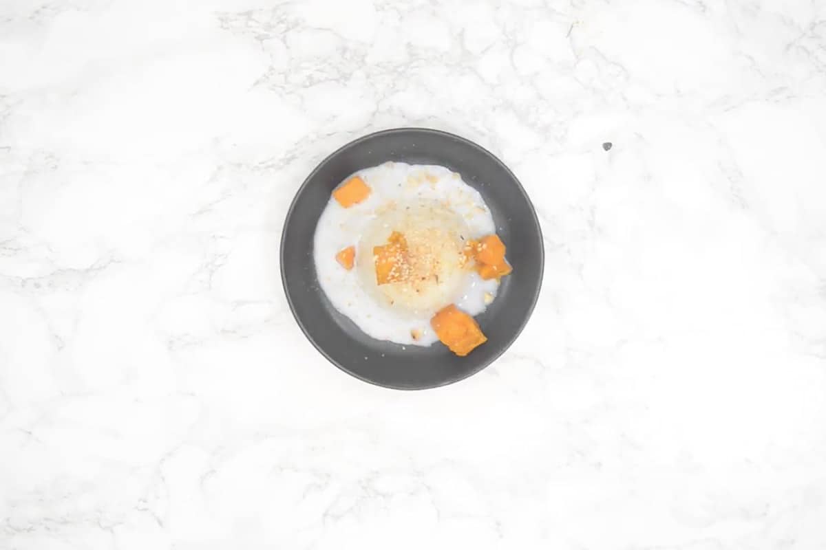 Coconut milk drizzled on top of rice along with mango cubes and sesame seeds.