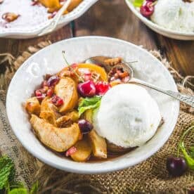Spiced fruit bake served in a bowl with a scoop of vanilla ice cream.