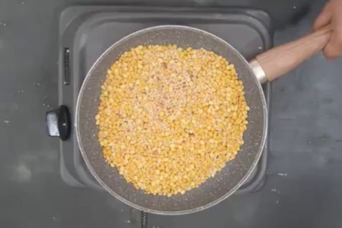 Chana dal and urad dal roasting in a pan.