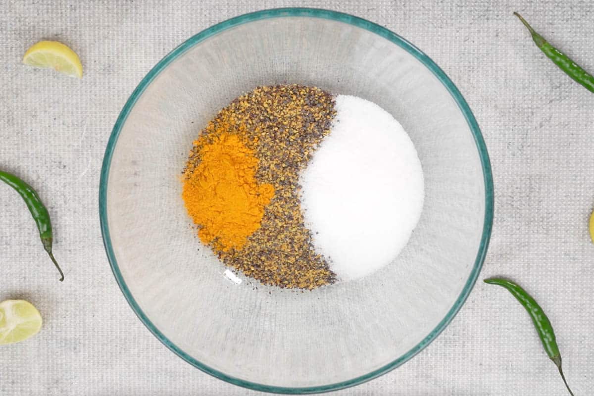 Ground mustard seeds, salt, and turmeric powder mixed in a bowl.
