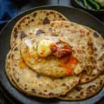 Aloo paratha is an Indian unleavened whole wheat flatbread stuffed with a spicy and super flavorful potato filling. It is one of the most popular breakfasts and is best enjoyed with plain yogurt, butter, and pickle. Check out my easy recipe with lots of variations, tips, and tricks.
