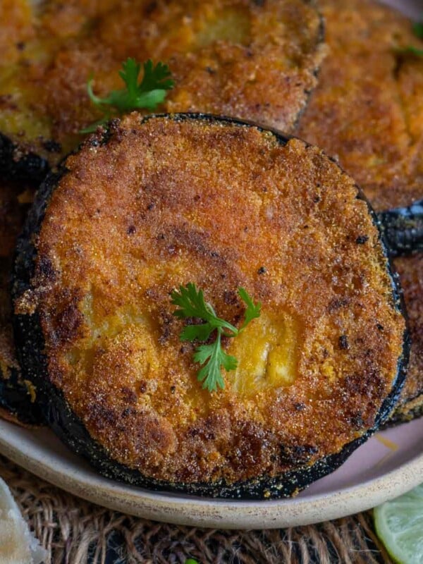Begun Bhaja (Bengali Style Fried Eggplant) are thick slices of eggplant coated with a spice mix and fried in mustard oil until crisp. Serve it with dal rice or luchi for a hearty meal (vegan, gluten-free).