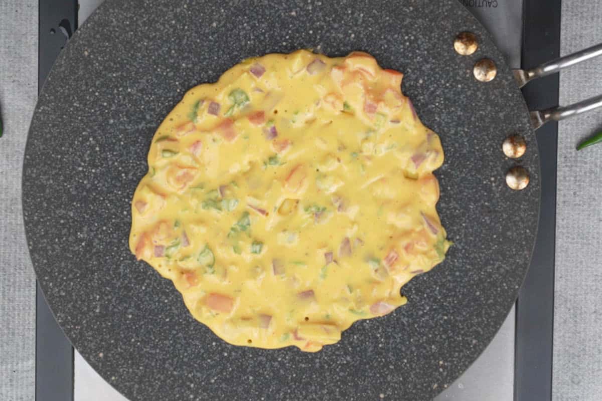 Batter poured on a hot tawa and spread to make a 5-6 inch circle.