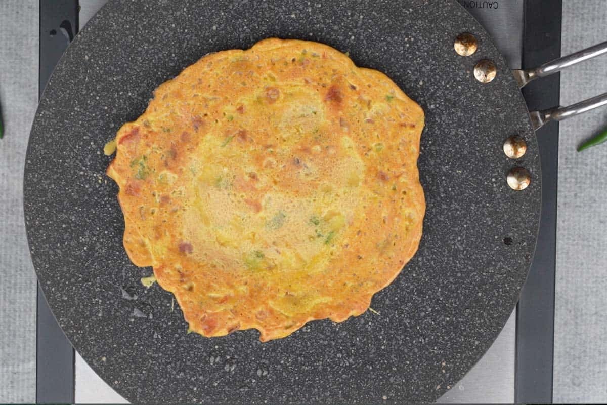 Besan chilla flipped on the hot tawa.