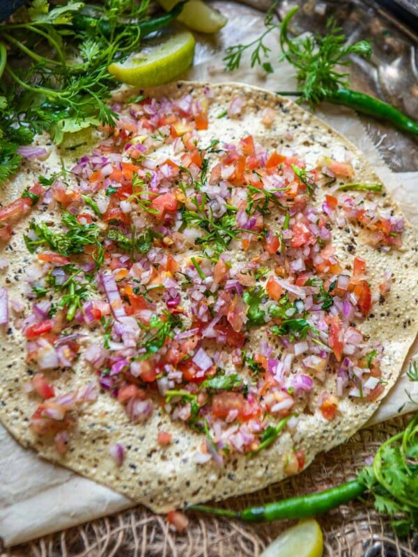 Masala Papad is a delicious Indian snack made using roasted or fried papad topped with a tangy and spicy onion tomato mix. Here is how to make it.