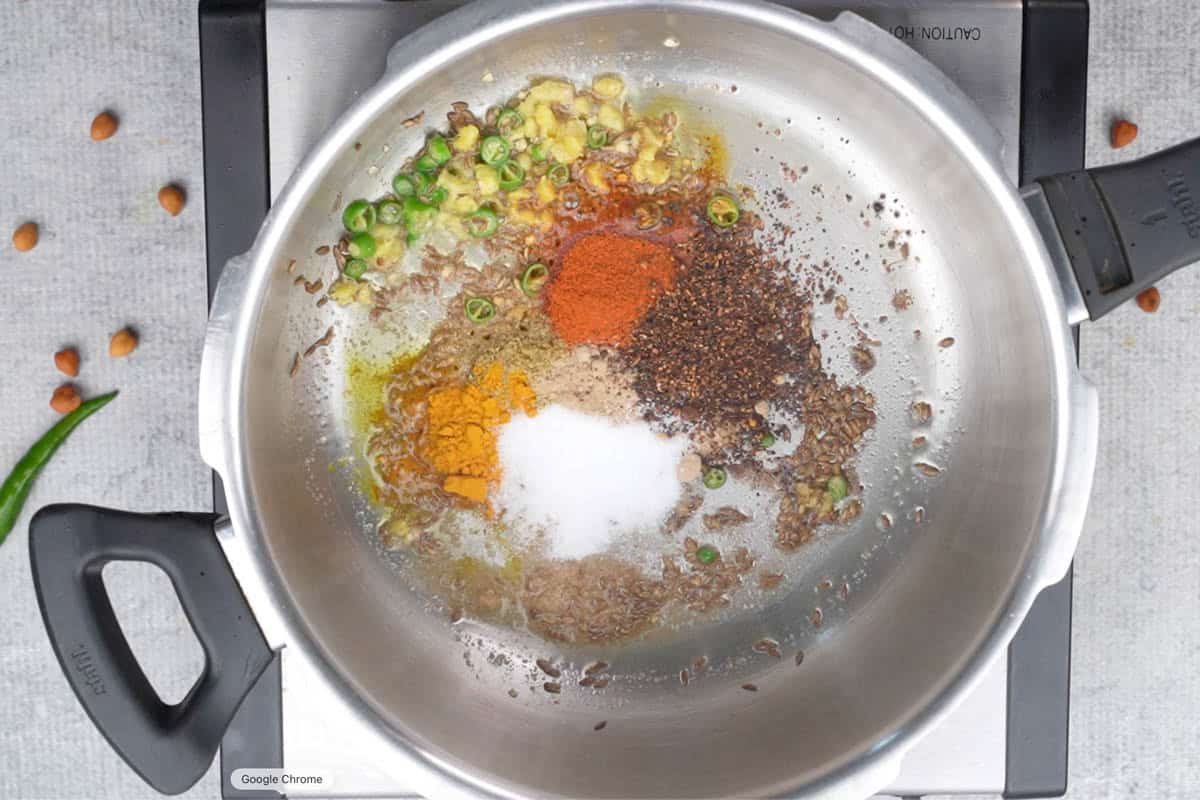 Tempering ingredients added to hot ghee in a pressure cooker.