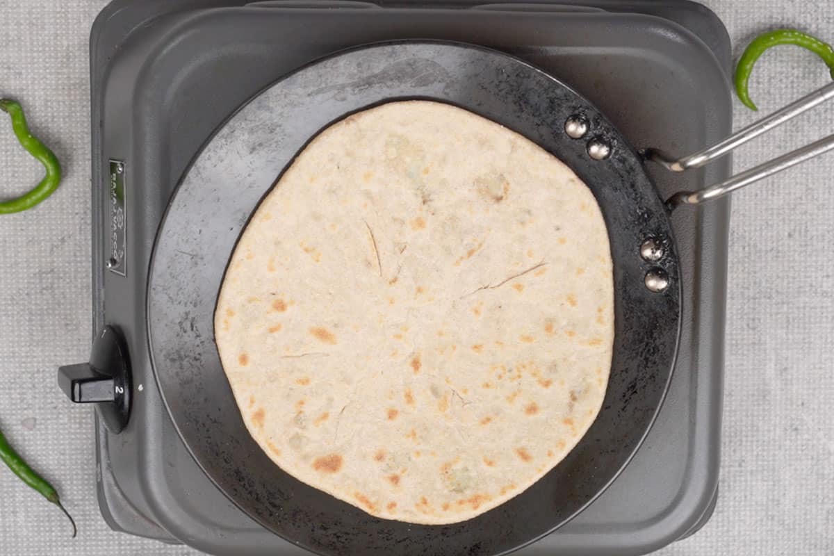 Cooking the paratha on a hot tawa.