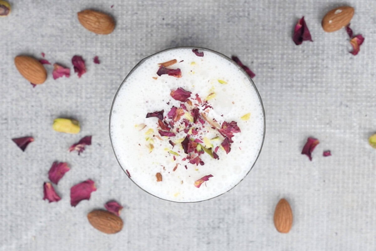 Lassi garnished with slivered almonds and pistachios and rose petals.