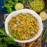 A bowl of Hurda Bhel with a lime half and a bowl of hurda in the background on a dark surface.