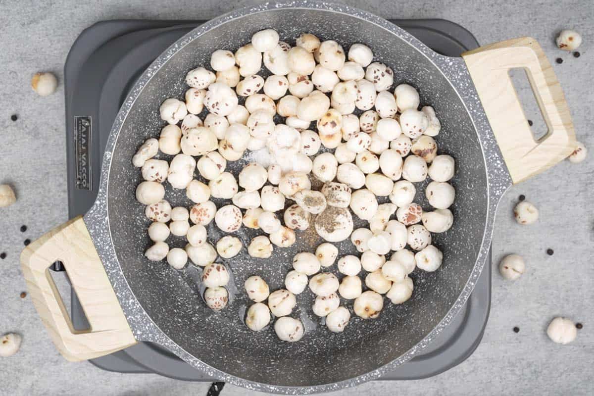 Makhana, salt and pepper added to the pan.