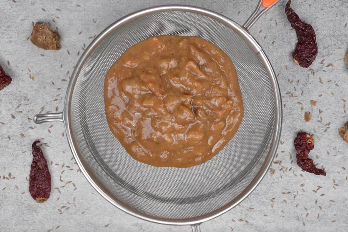Straining the tamarind pulp through a mesh strainer.