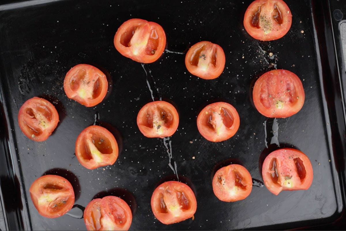 Tomato halves arranged on a baking tray and drizzled with extra virgin olive oil, salt and pepper.