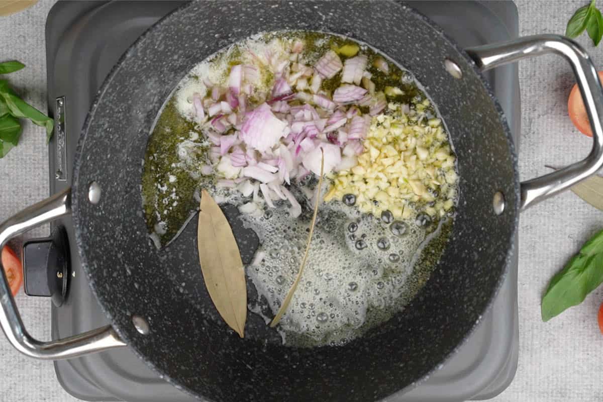 Garlic, onions and bay leaves added to the pan.
