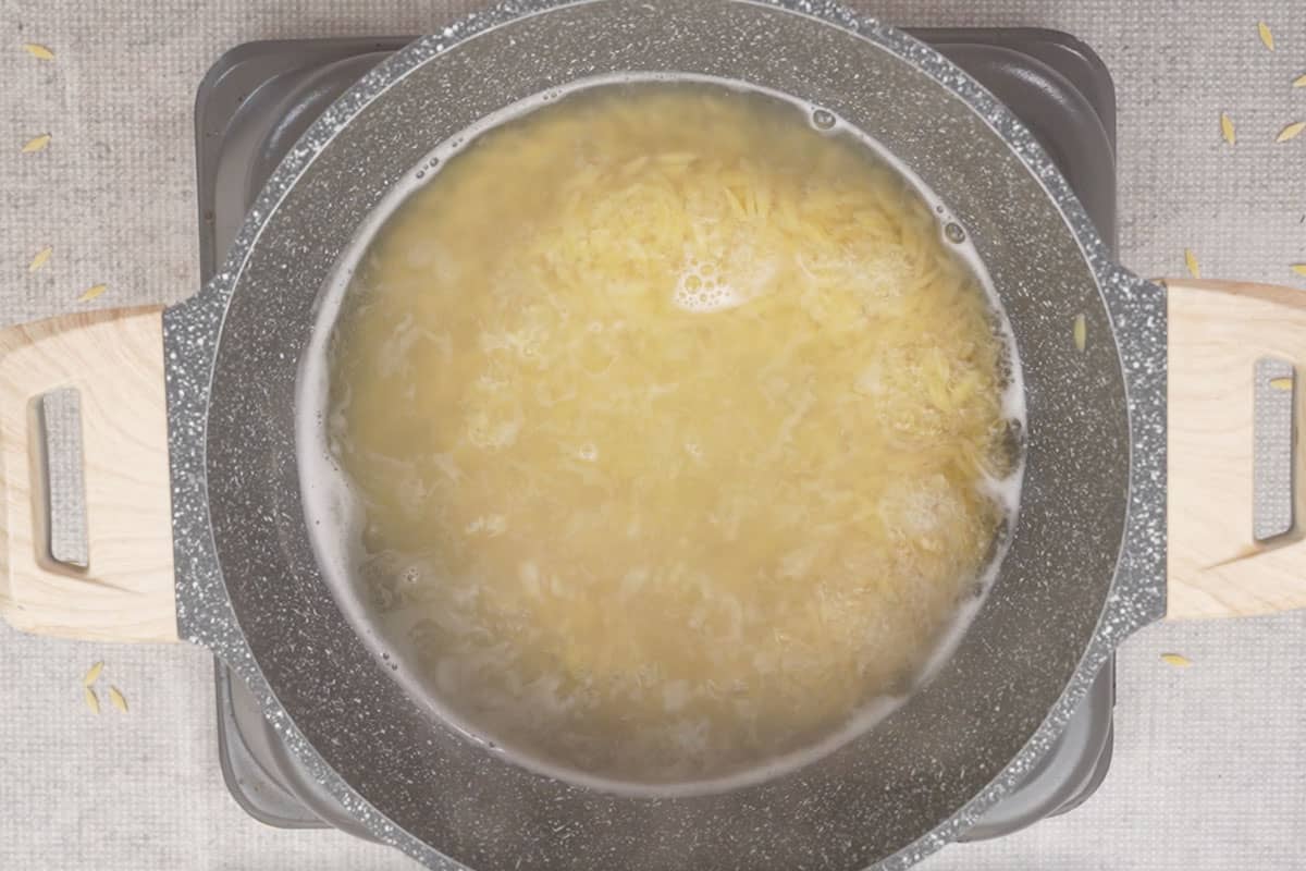 Pasta cooking in water in a pan.