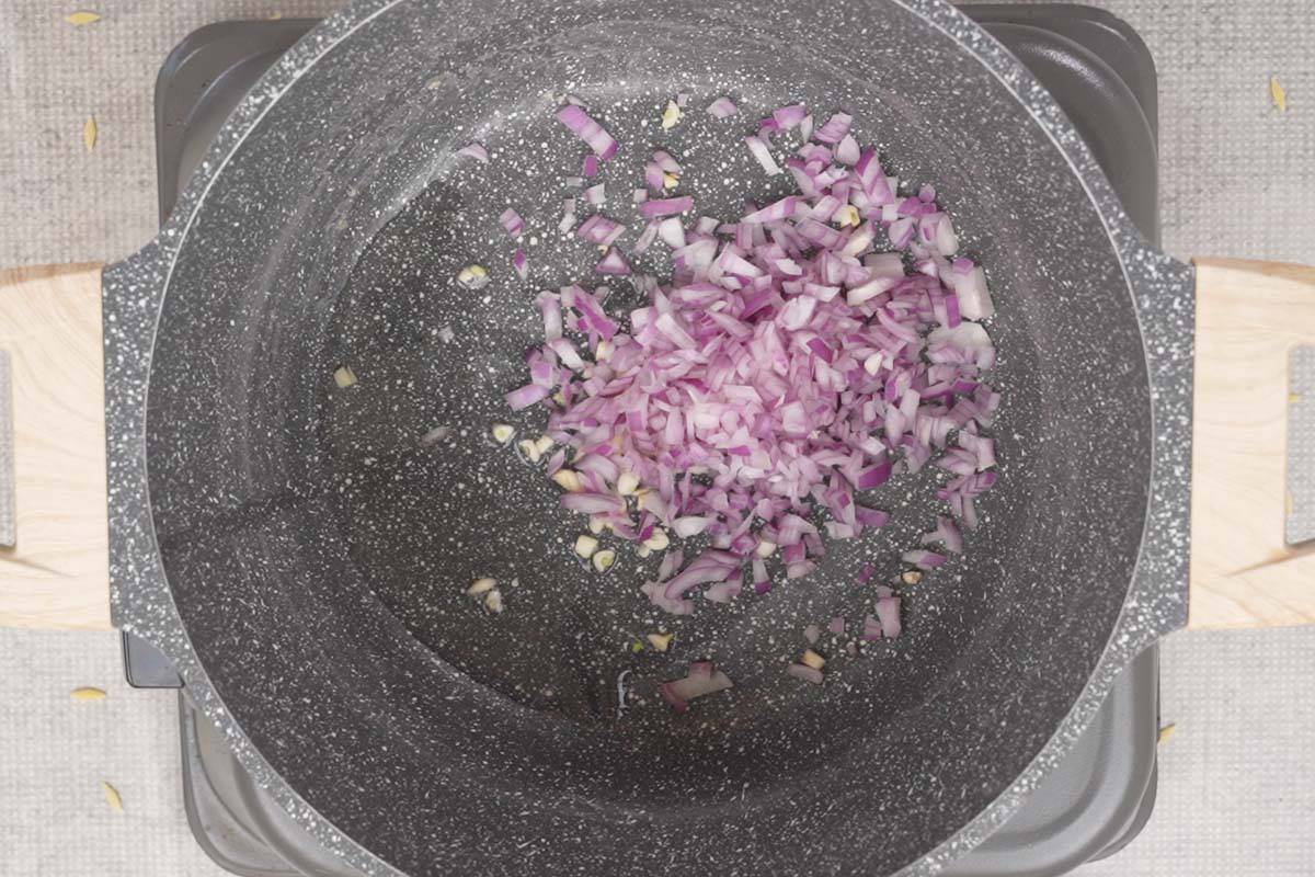 Onion and garlic added to hot oil in a pan.
