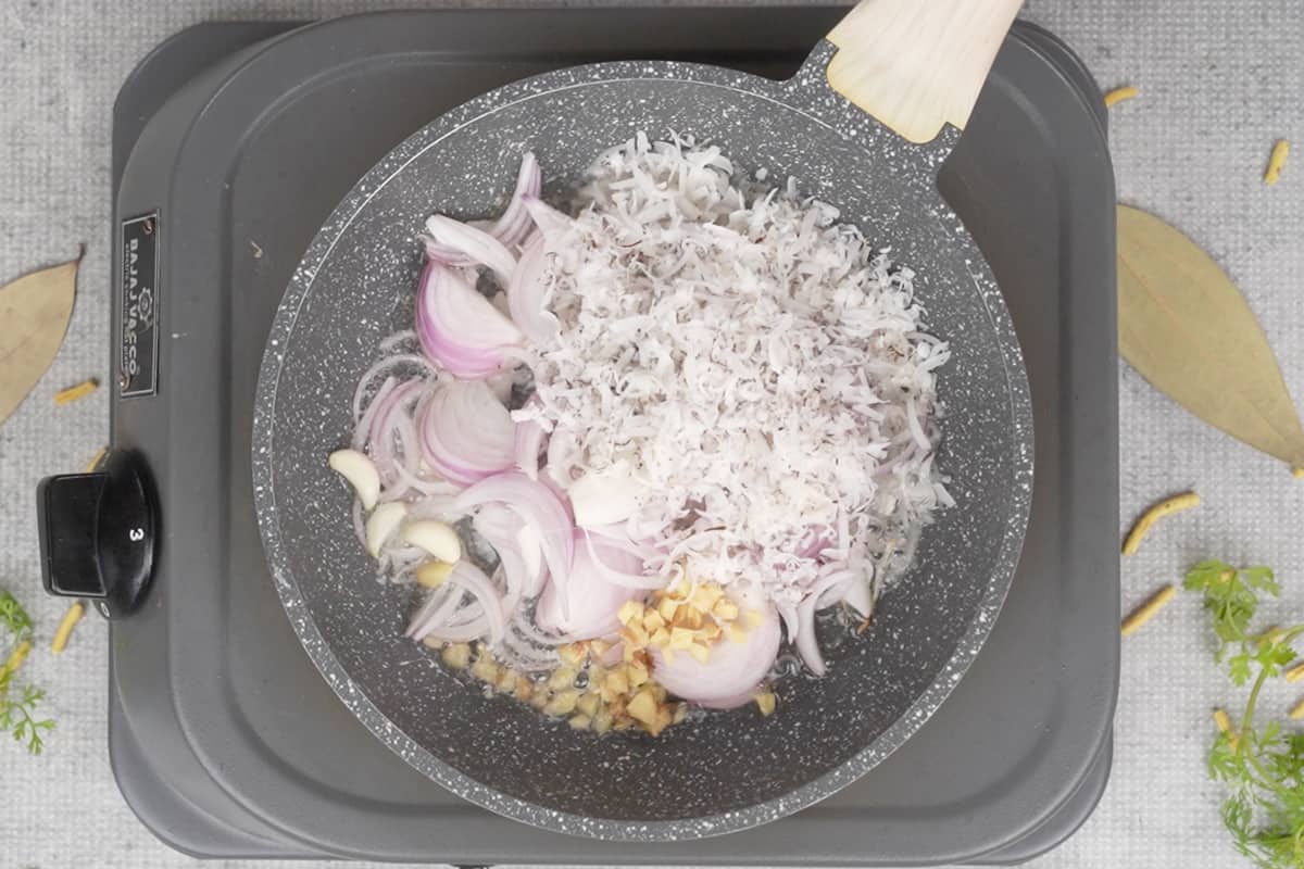 Onions, ginger, garlic and coconut added to hot oil in a pan.