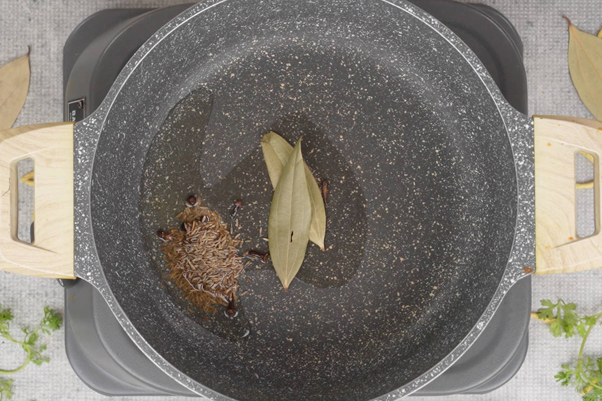 Whole spices added to hot oil in a pan.