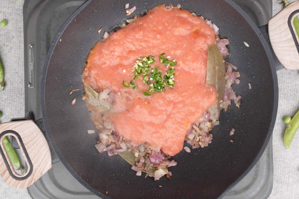 Pureed tomatoes and green chilies added to the pan.