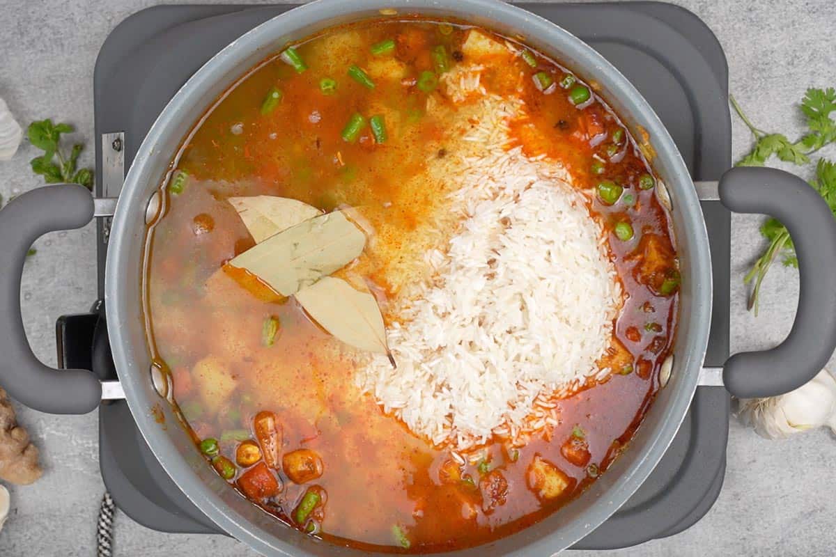 soaked rce, water, lim juice and bay leaves aded to the pan.