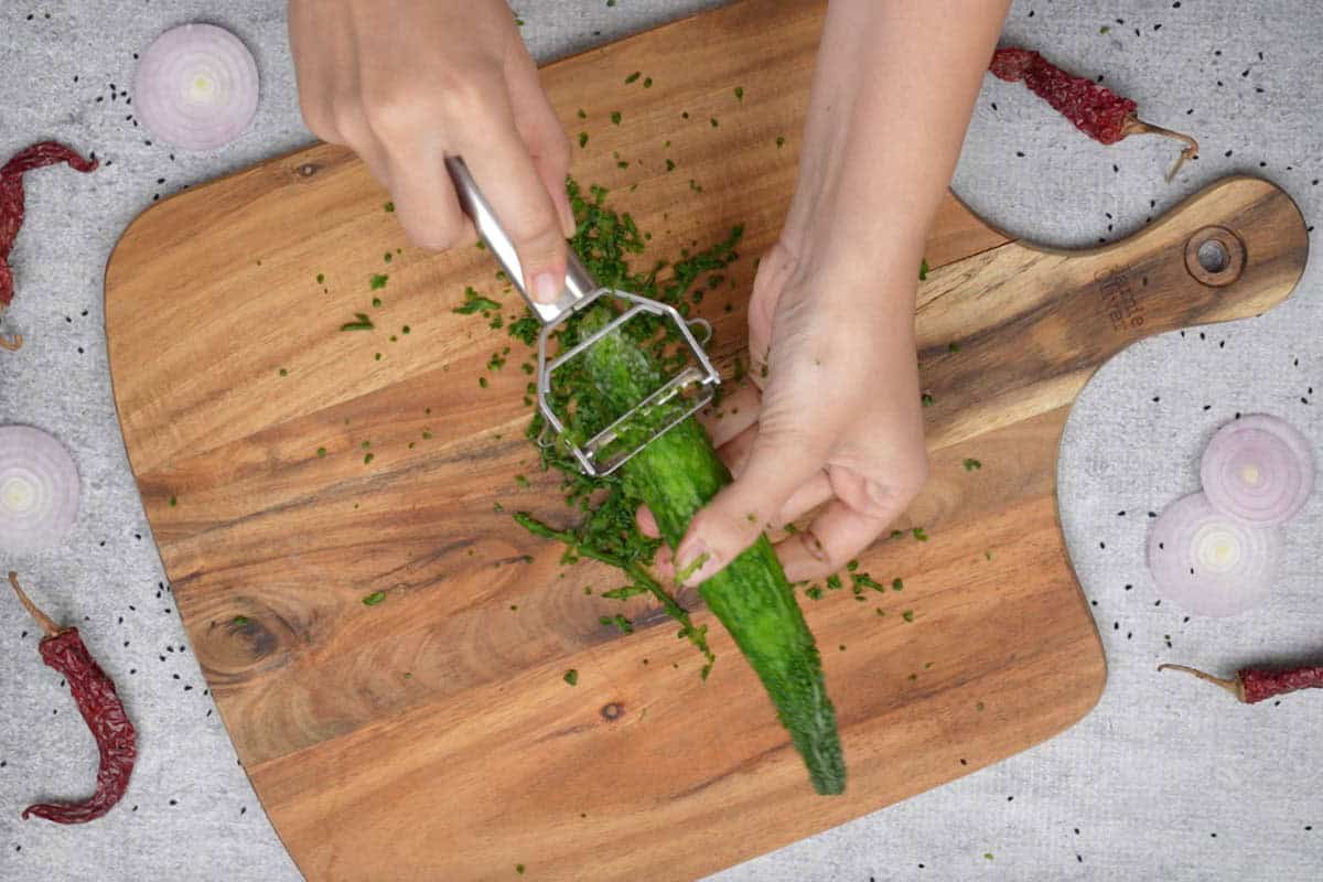 Peeling the karela using a vegetable peeler.