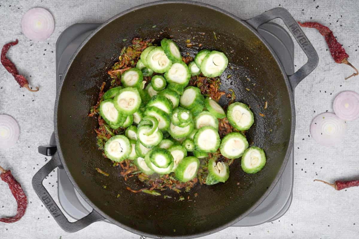 Sliced karela added to the pan.