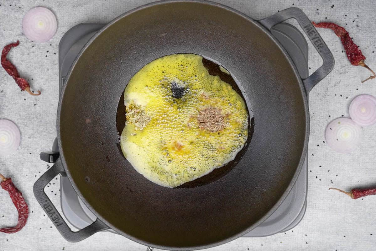 Spices added to hot oil in a pan.