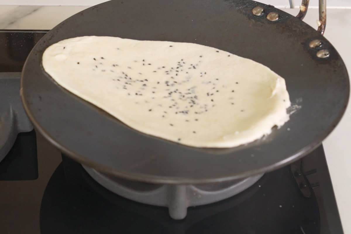 Naan transferred to the hot tawa with water side down.