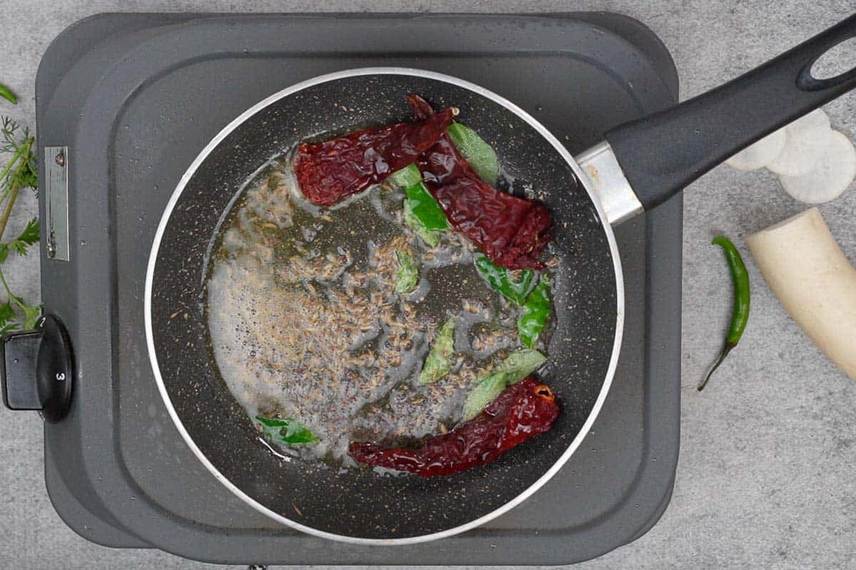 Tempering ingredients added to hot oil in a pan.