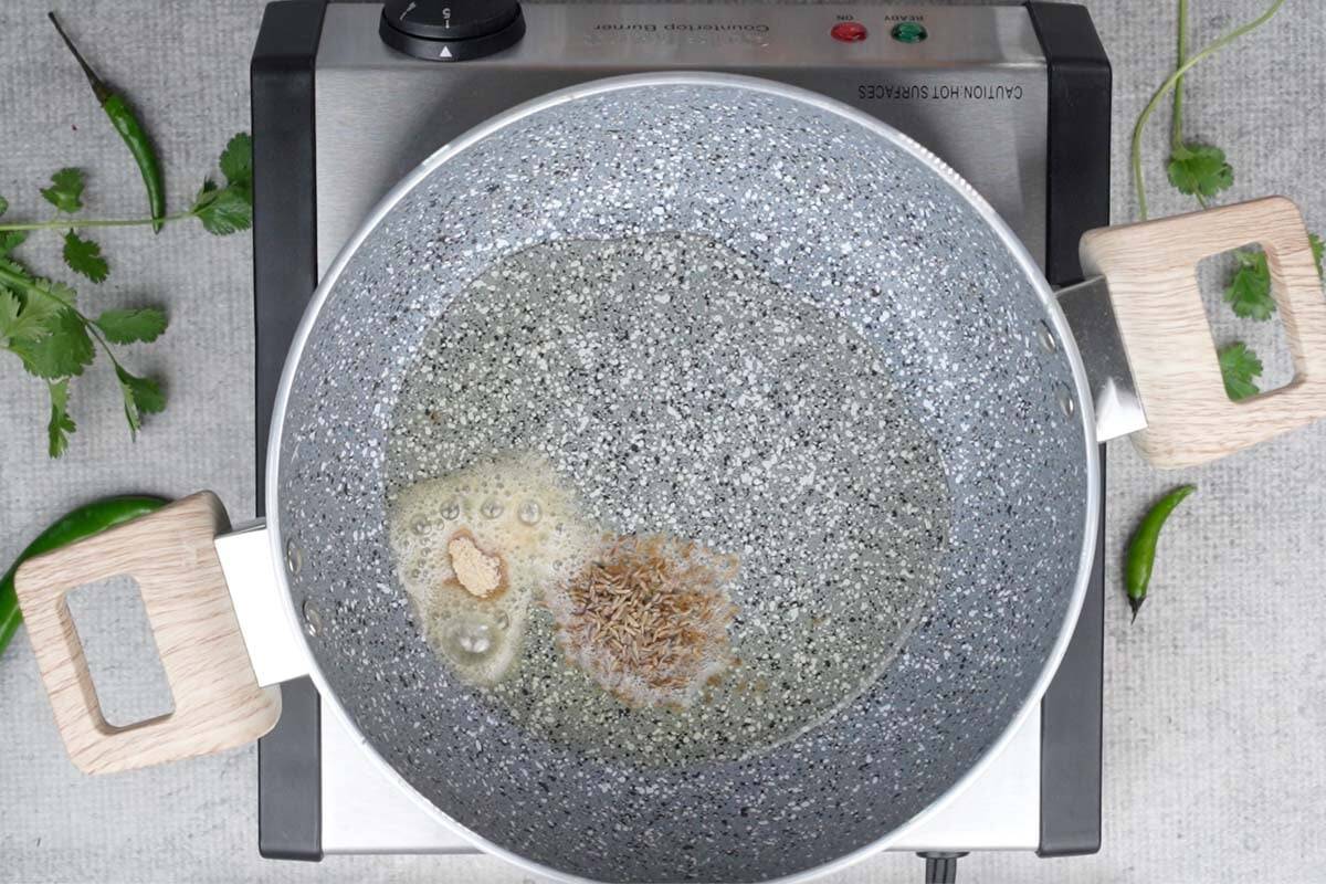 Hing and cumin seeds added to hot oil in the pan.