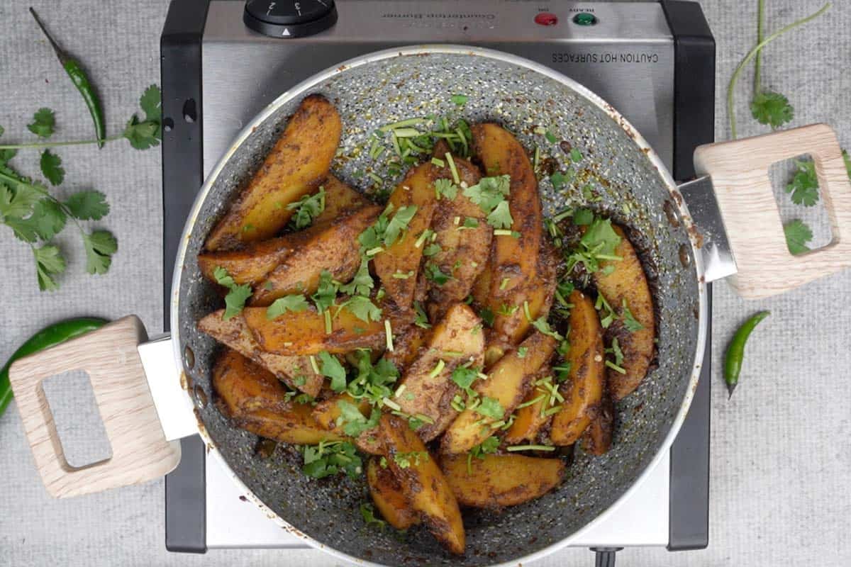 Ready aloo anardana garnished with chopped cilantro.