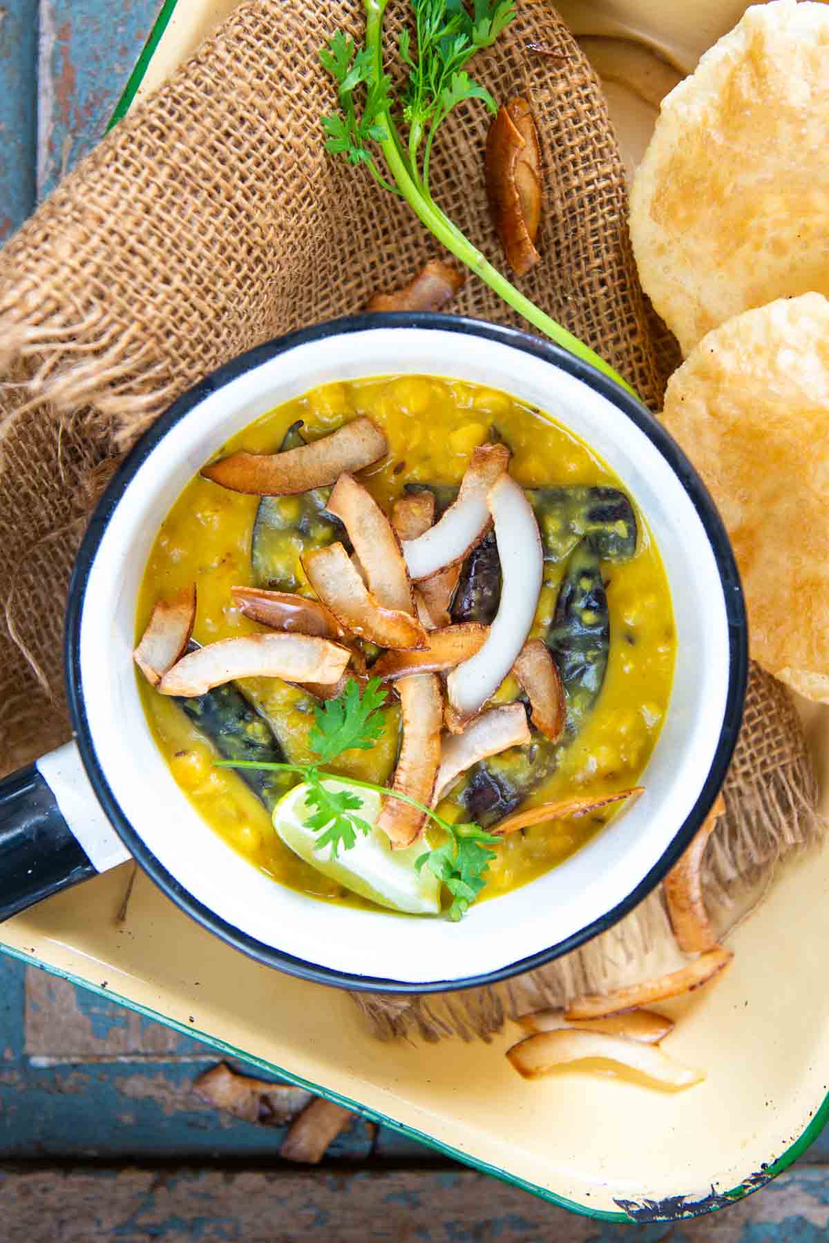 Cholar dal served in a pan with luchi kept on the side.