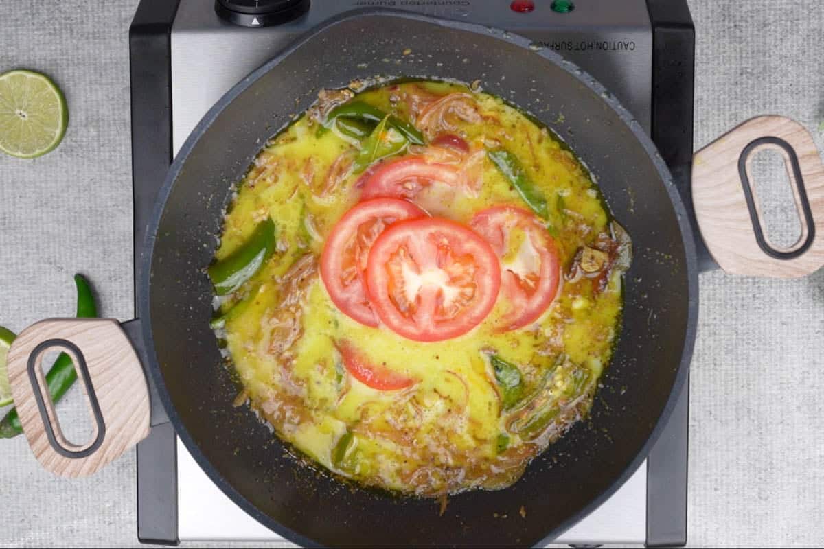 Thin coconut milk and tomato added to the pan.