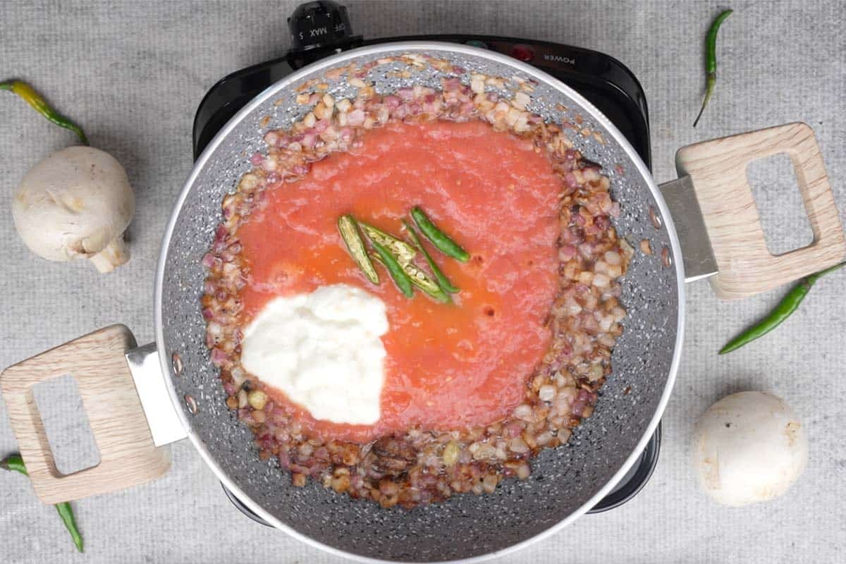 Tomato, yogurt and green chilies added to the pan.