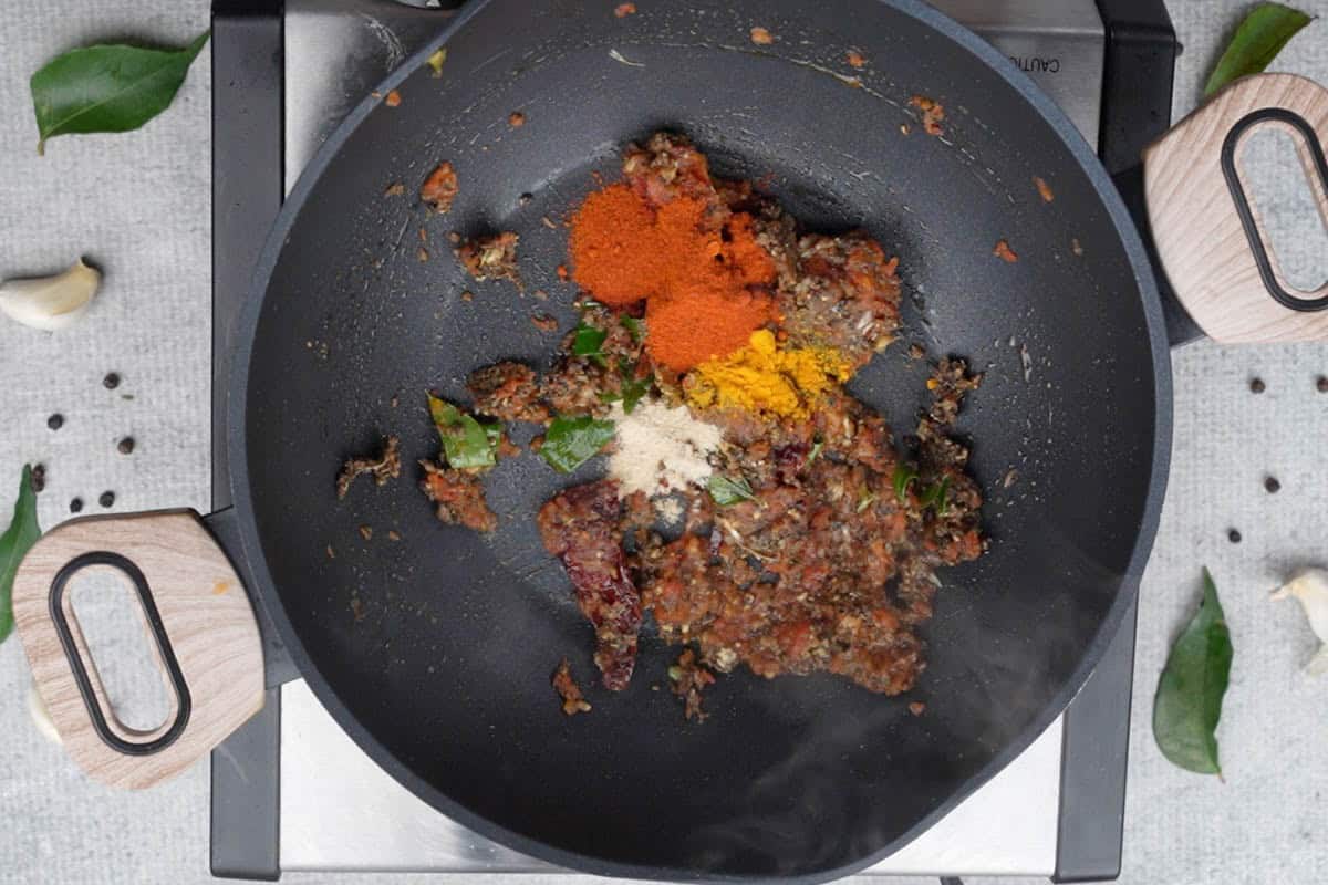 Turmeric powder, red chili powder and hing added to the pan.